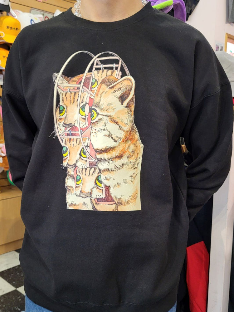 Black sweatshirt with a colorful graphic of a cat on a mannequin in a store setting.