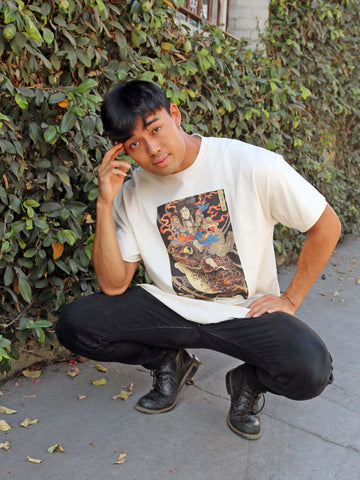 A model wearing a beige t-shirt with an ukiyoe frog and samurai on it.