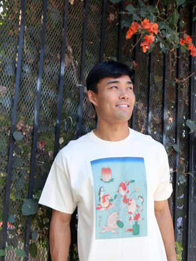 A model wearing a beige t-shirt with Japanese ukiyoe goldfish dancing.