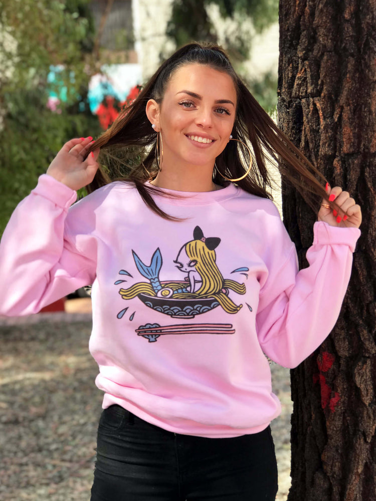 Model wearing a pink sweater with a kawaii mermaid on it.