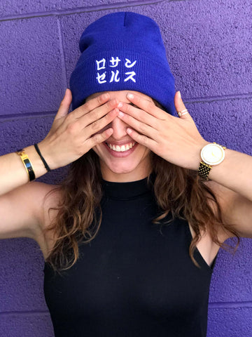 A model wearing a blue beanie that reads 'Los Angeles' in Japanese.