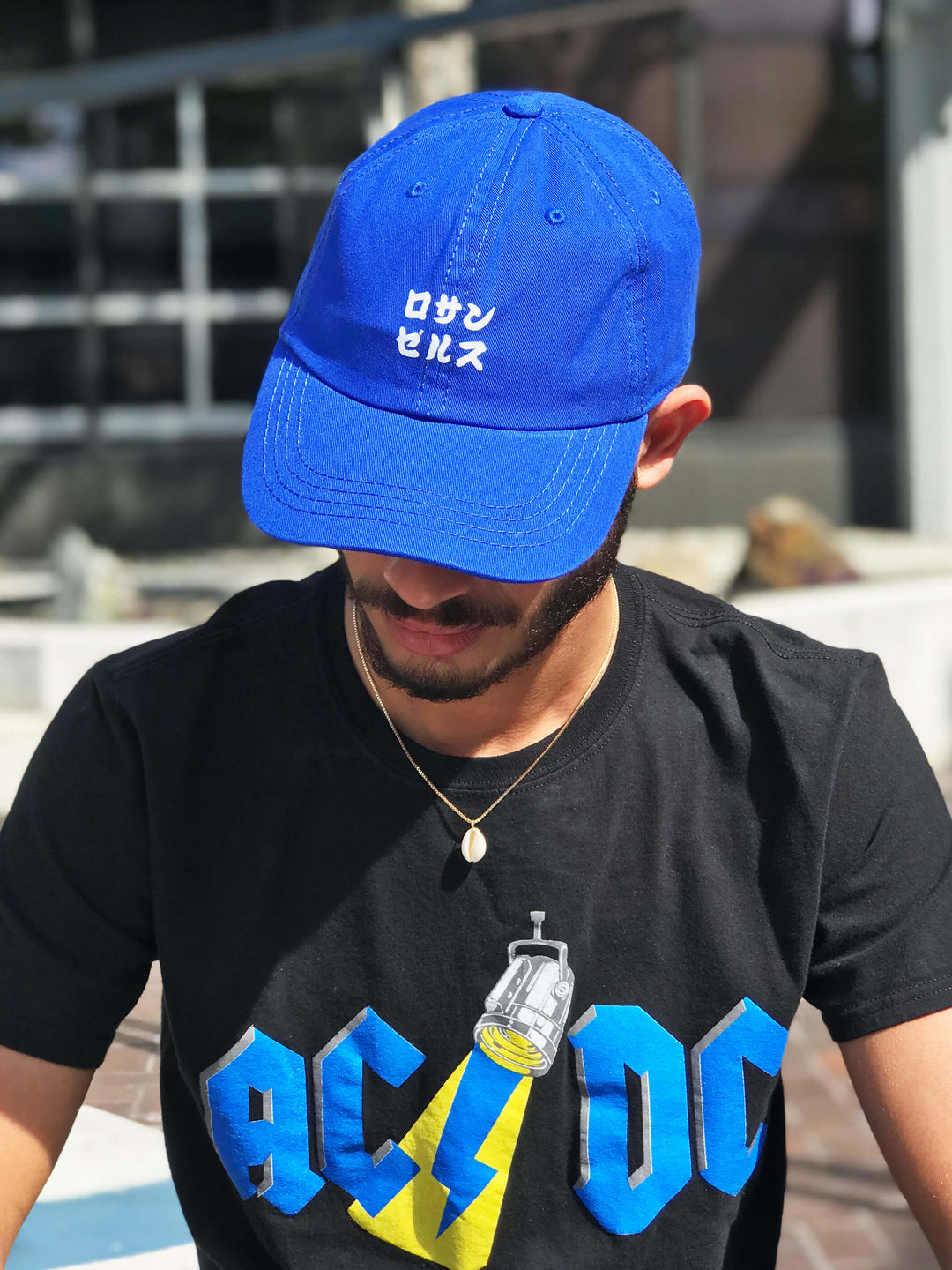 A model wearing a blue baseball cap that reads 'Los Angeles' in Japanese.