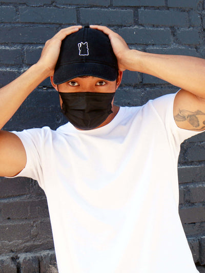 A model wearing an embroidered polo hat with a maneki neko on it.