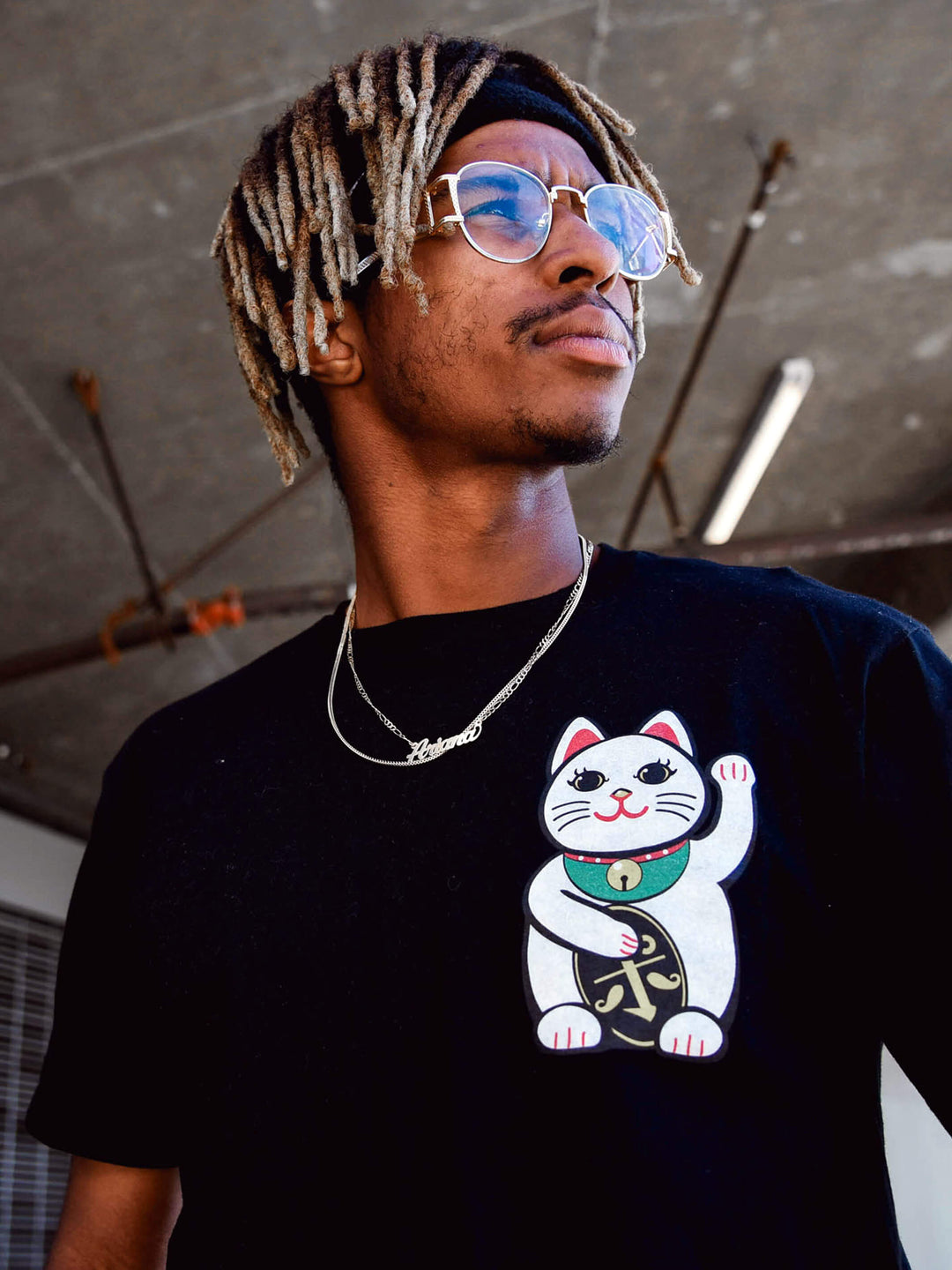A model wearing a black t-shirt with a lucky cat printed on the chest.