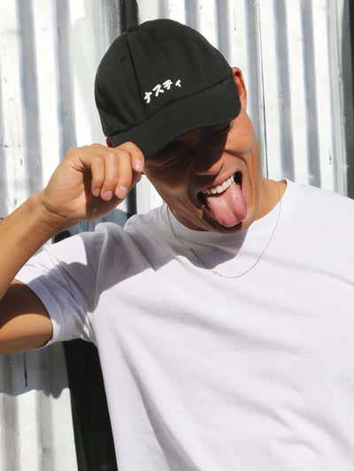 A black polo cap that says nasty in Japanese.