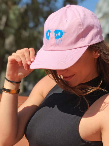 A pink kawaii polo cap with crying anime eyes on it.