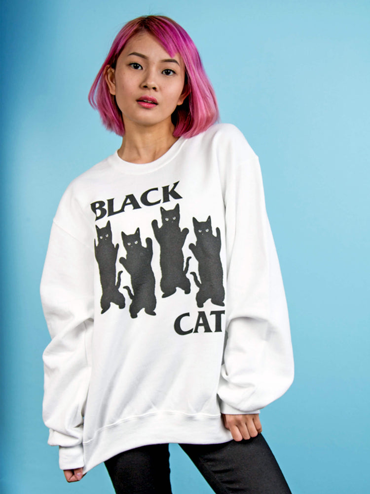 Model wearing an oversized sweatshirt with dancing black cats on it.