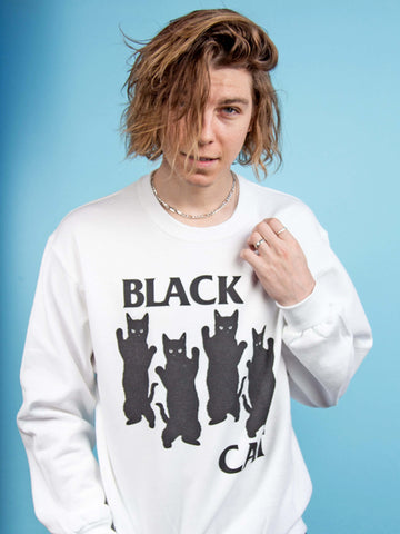 Model wearing a white sweatshirt with black cats on it.