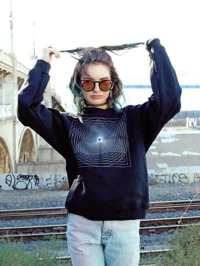A model wearing a black sweater with a trippy geometric design on it.