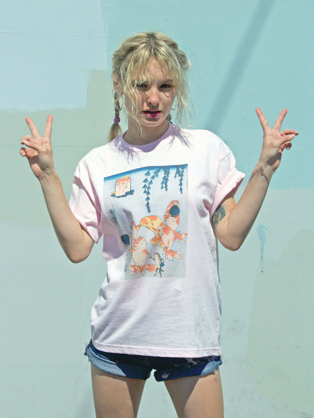 Model wearing pink graphic tee with Japanese goldfish on it.
