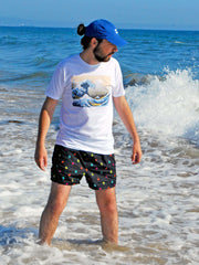 A model in the water wearing a white graphic tee with the Japanese Hokusai wave print.