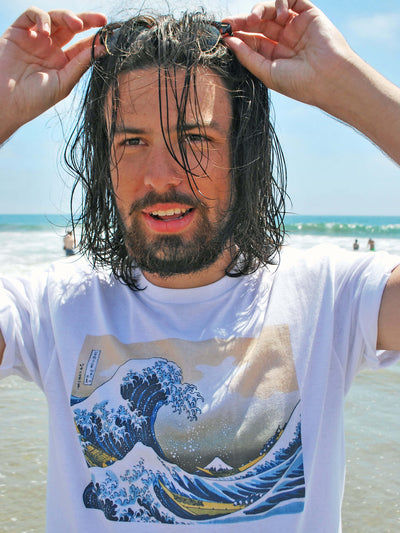 A model on the beach wearing a white t-shirt with the famous great wave on it.