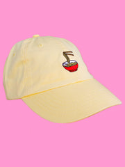 Yellow foodie polo cap with embroidered ramen bowl on it.
