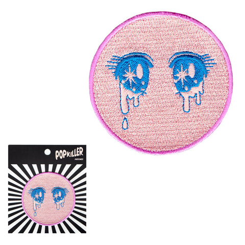 A pink circle patch with kawaii anime eyes on it.