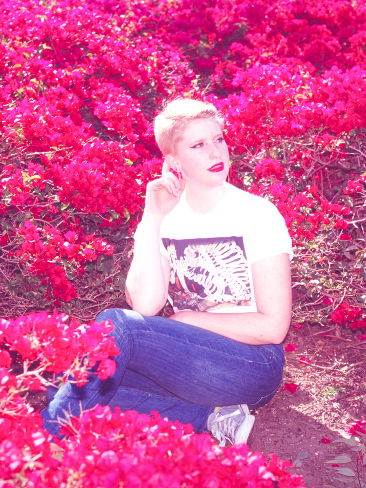 A model surrounded by flowers wearing a Japanese skeleton graphic t-shirt.