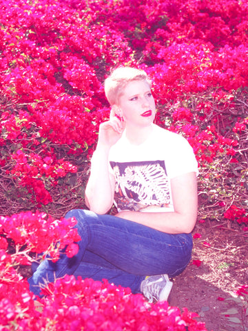 A model surrounded by flowers wearing a Japanese skeleton graphic t-shirt.